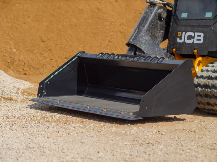 Black JCB loader bucket on gravel.