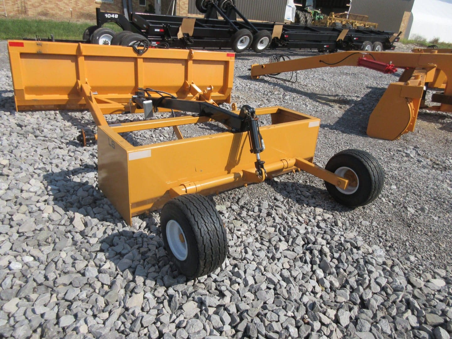 Yellow box blade on gravel driveway.