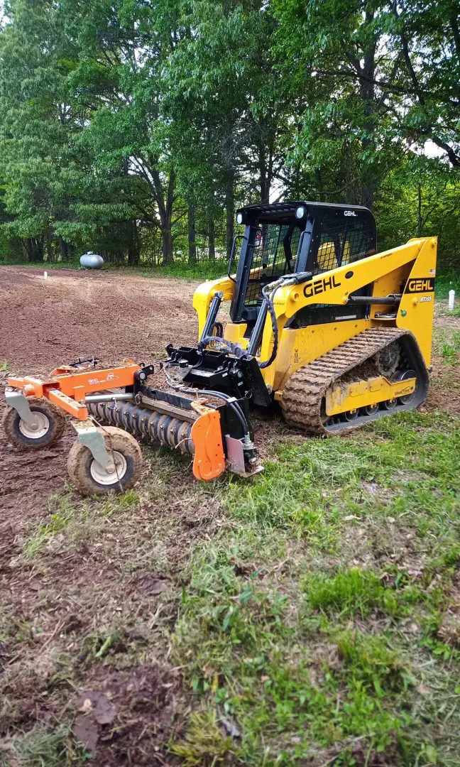 Yellow Gehl skid steer with tiller attachment.