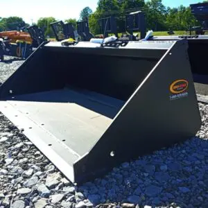 Black tractor bucket on gravel ground.