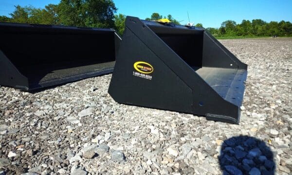 Black excavator bucket on gravel.