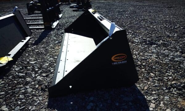 Black metal tractor bucket on gravel.