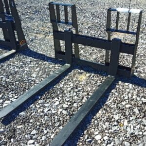 Black metal pallet forks on gravel.