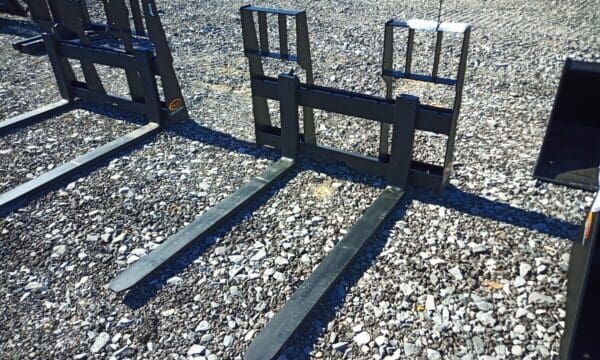 Black metal pallet forks on gravel.