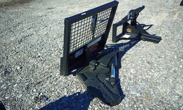 Black tractor grapple attachment on gravel.