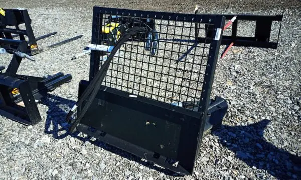 Black metal skid steer attachment with a mesh cage.