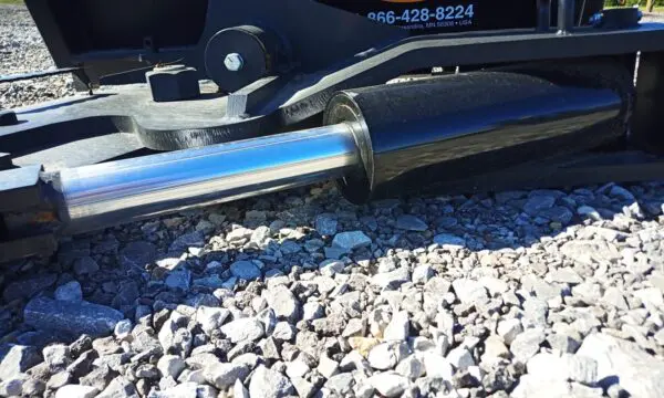 Close-up of a hydraulic cylinder on gravel.