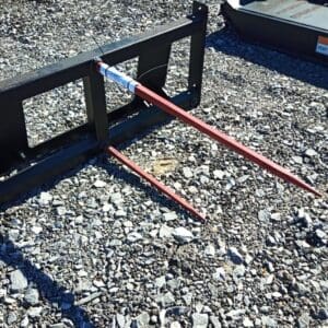 Black metal hay spear on gravel.