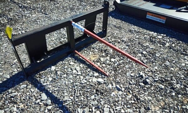 Black metal hay spear on gravel.