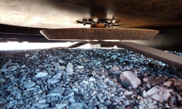 Closeup of a mower blade over gravel.