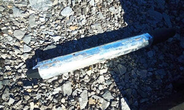 Metal rod on a gravel surface.