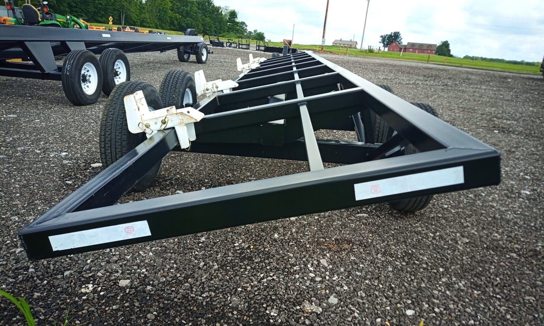 Black trailer with white tires on gravel.