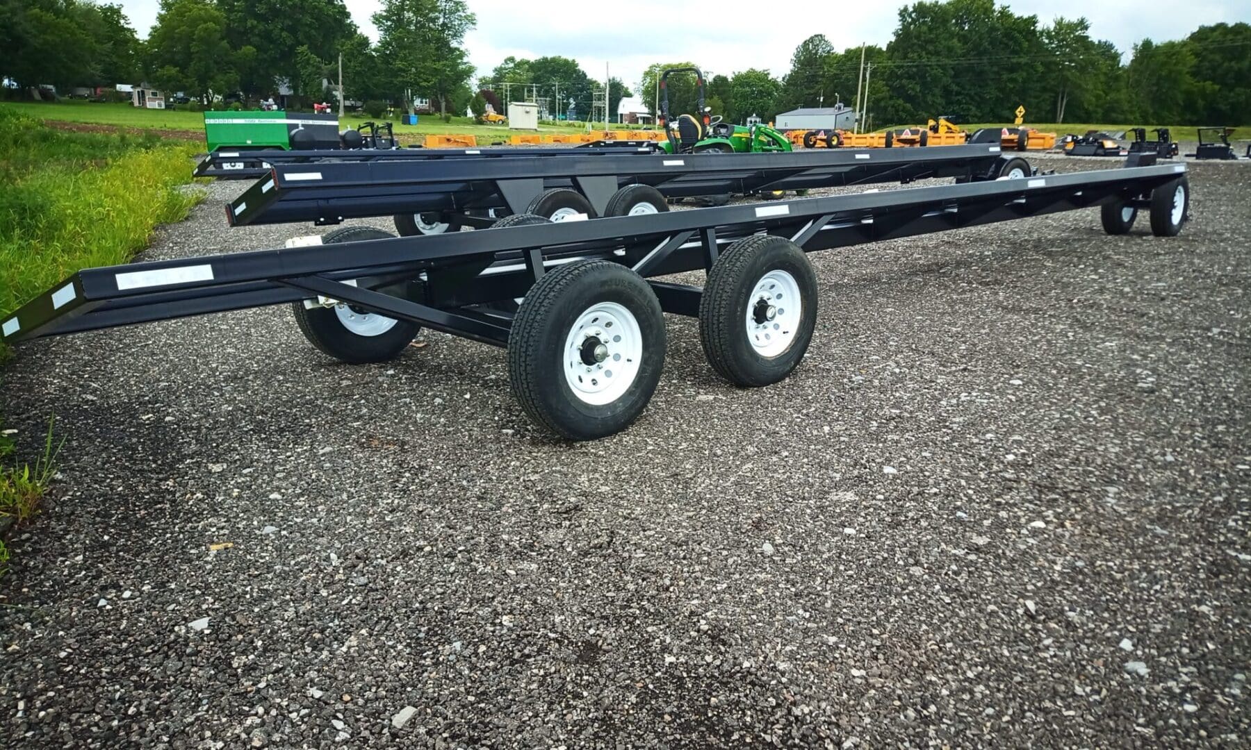 Black farm trailer with large wheels.