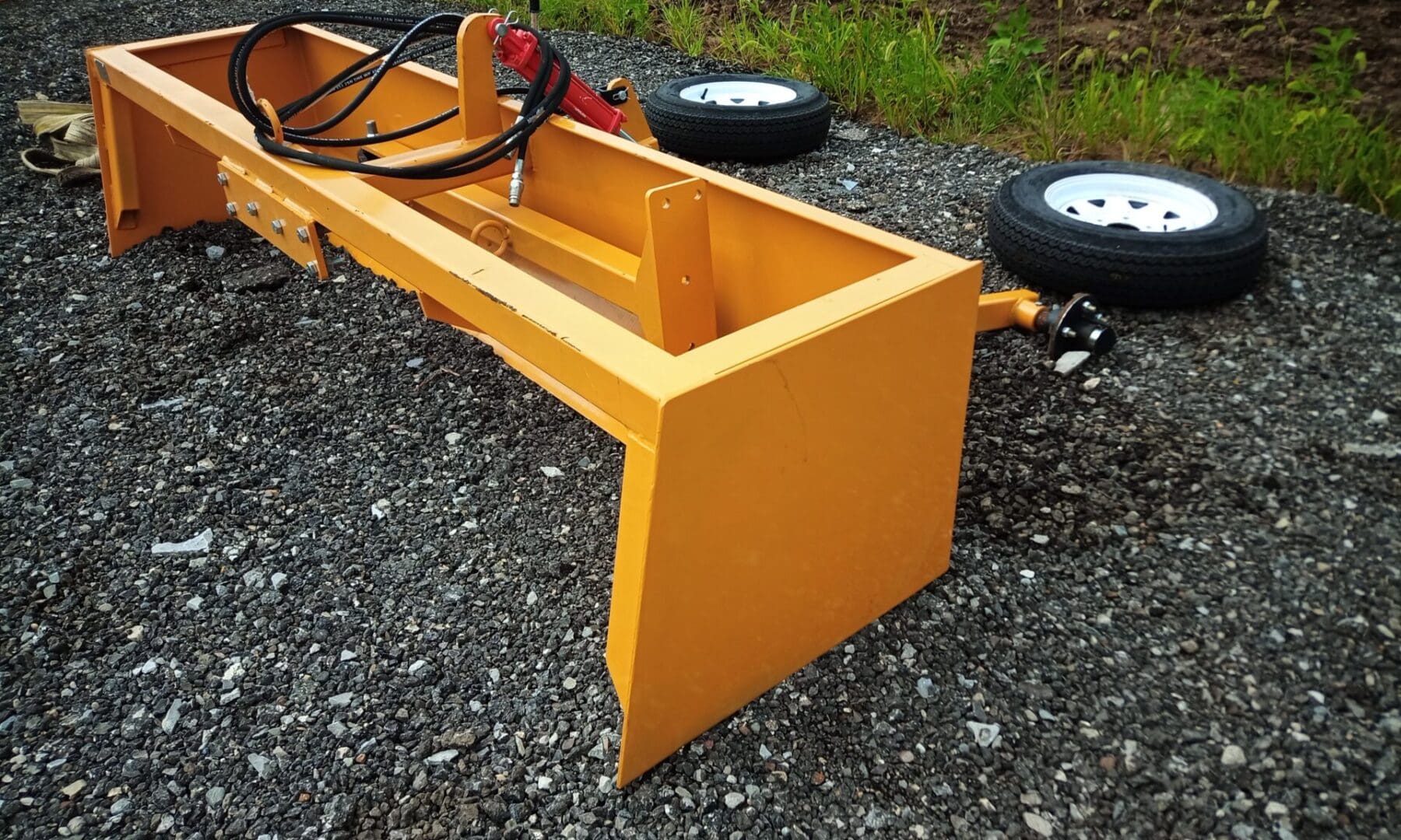 Yellow tractor attachment on gravel.