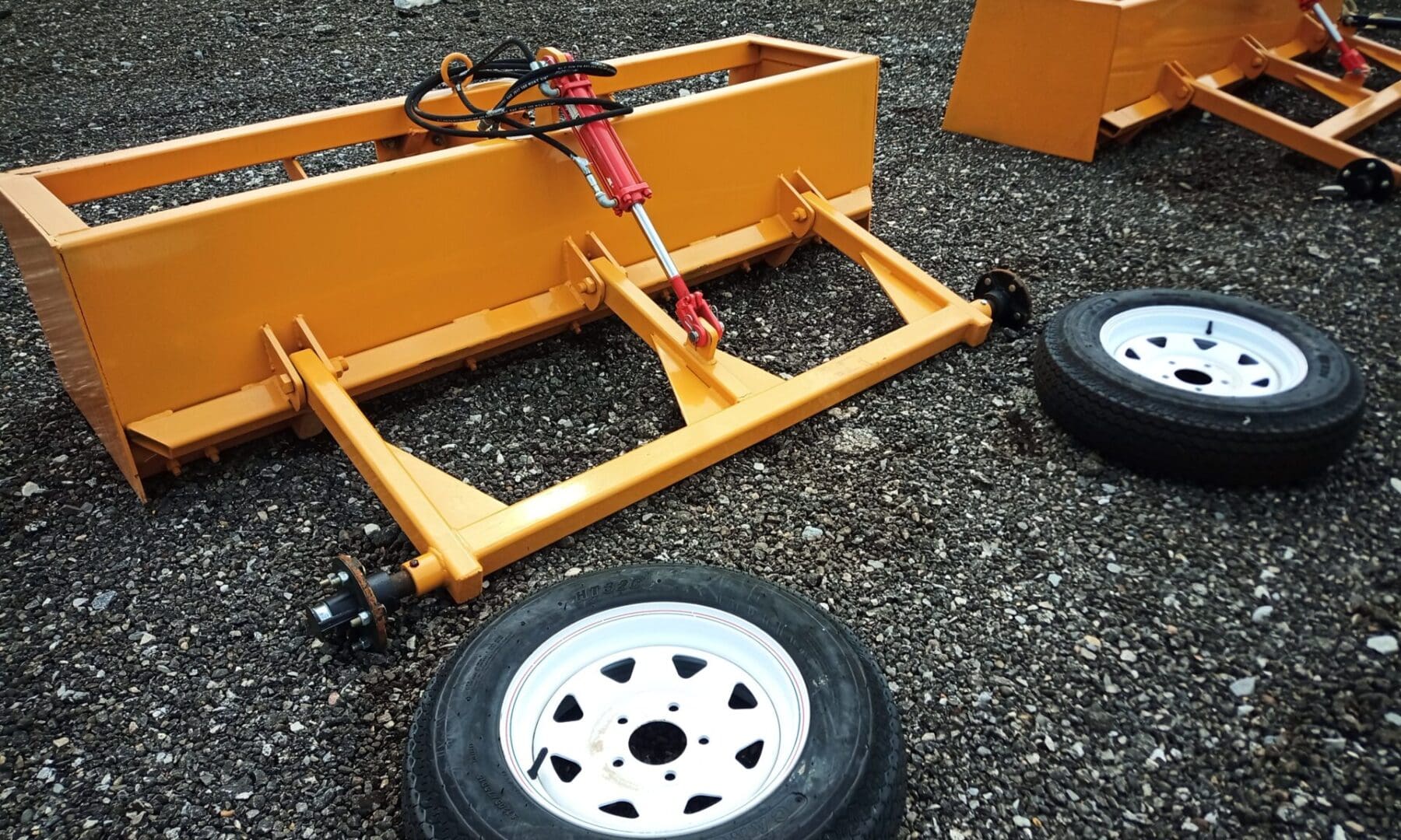 Yellow farm equipment with wheels and a hydraulic lift.