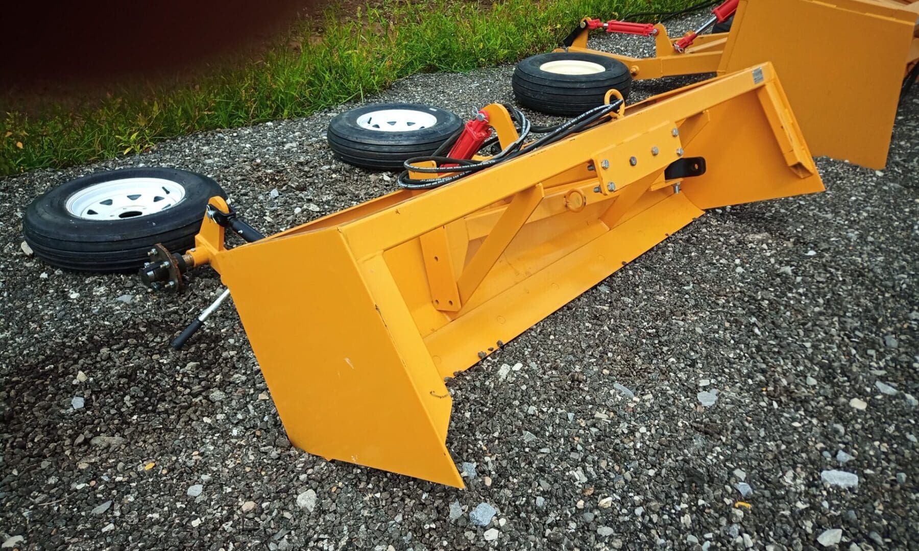 Yellow tractor attachment on gravel.