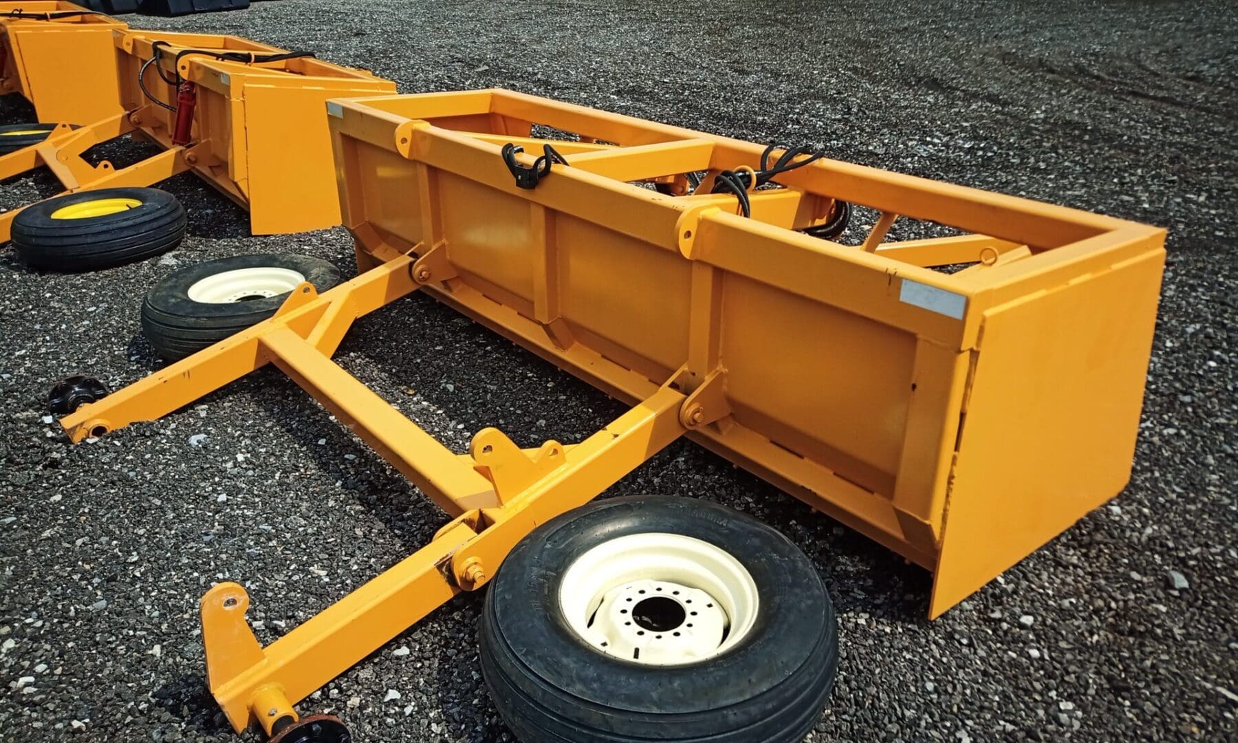 Yellow farm equipment on gravel ground.