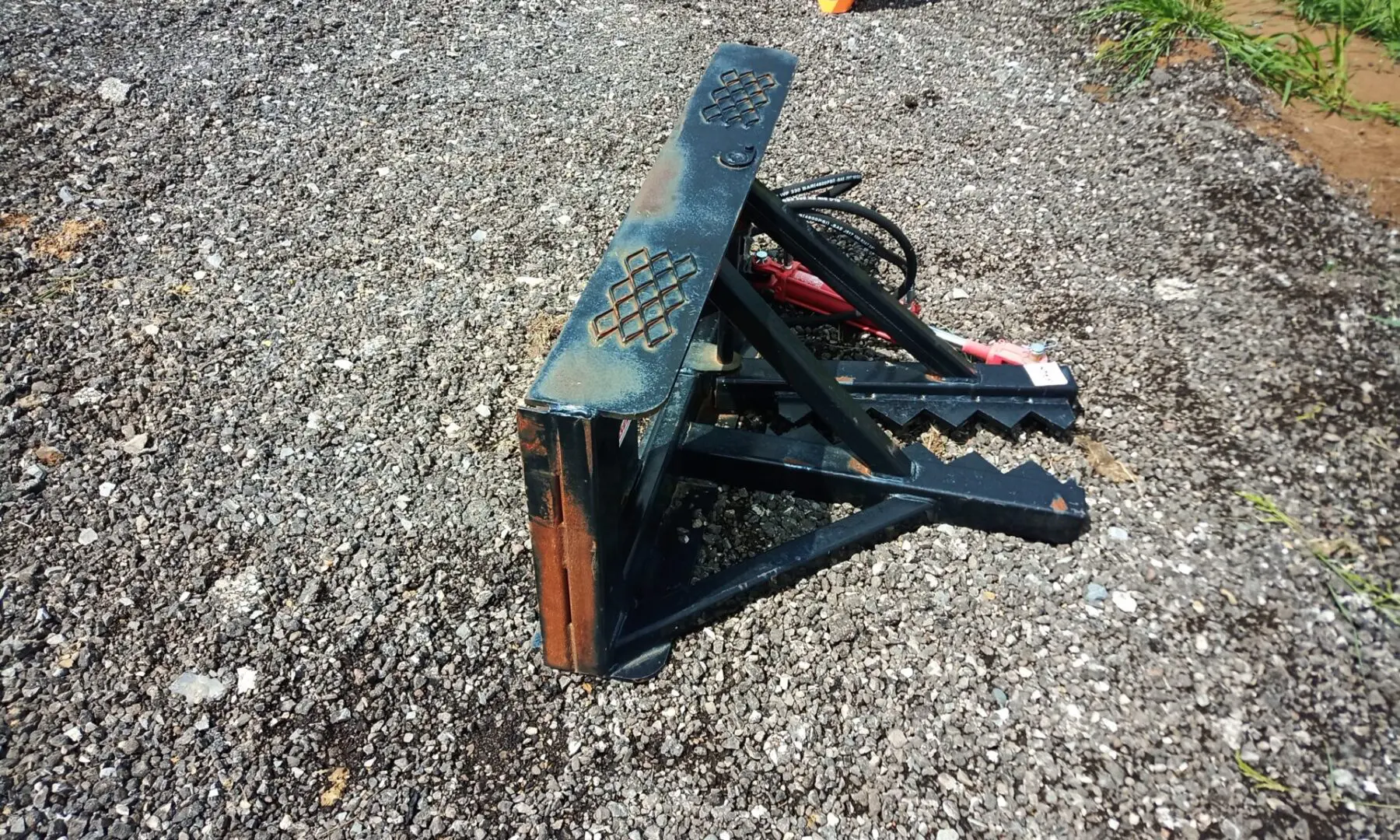 Black tree grapple on gravel ground.