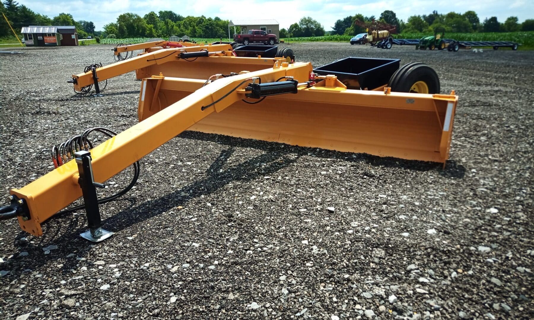 Yellow grader parked on gravel lot.