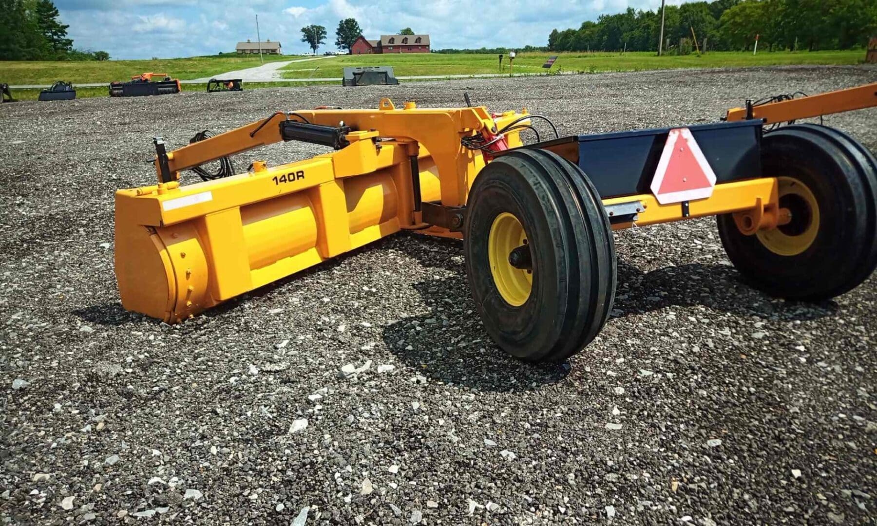 Yellow farm equipment on gravel ground.