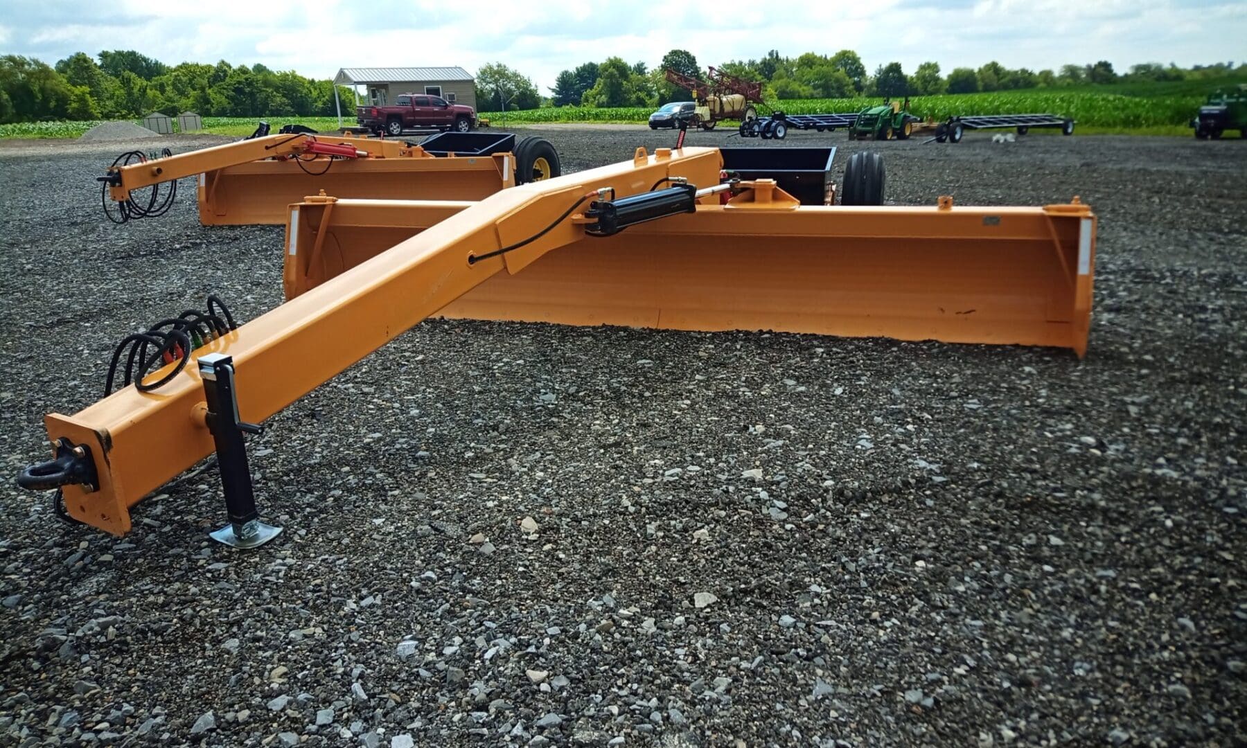 Yellow grader blade on gravel ground.