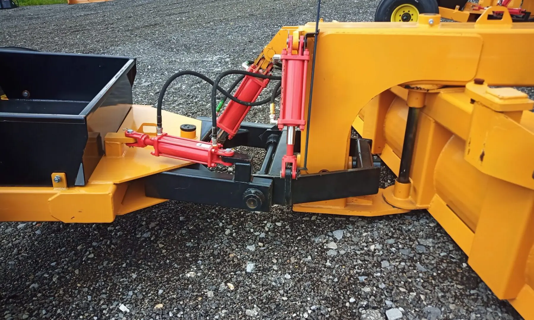 Yellow and black hydraulic snow plow attachment.