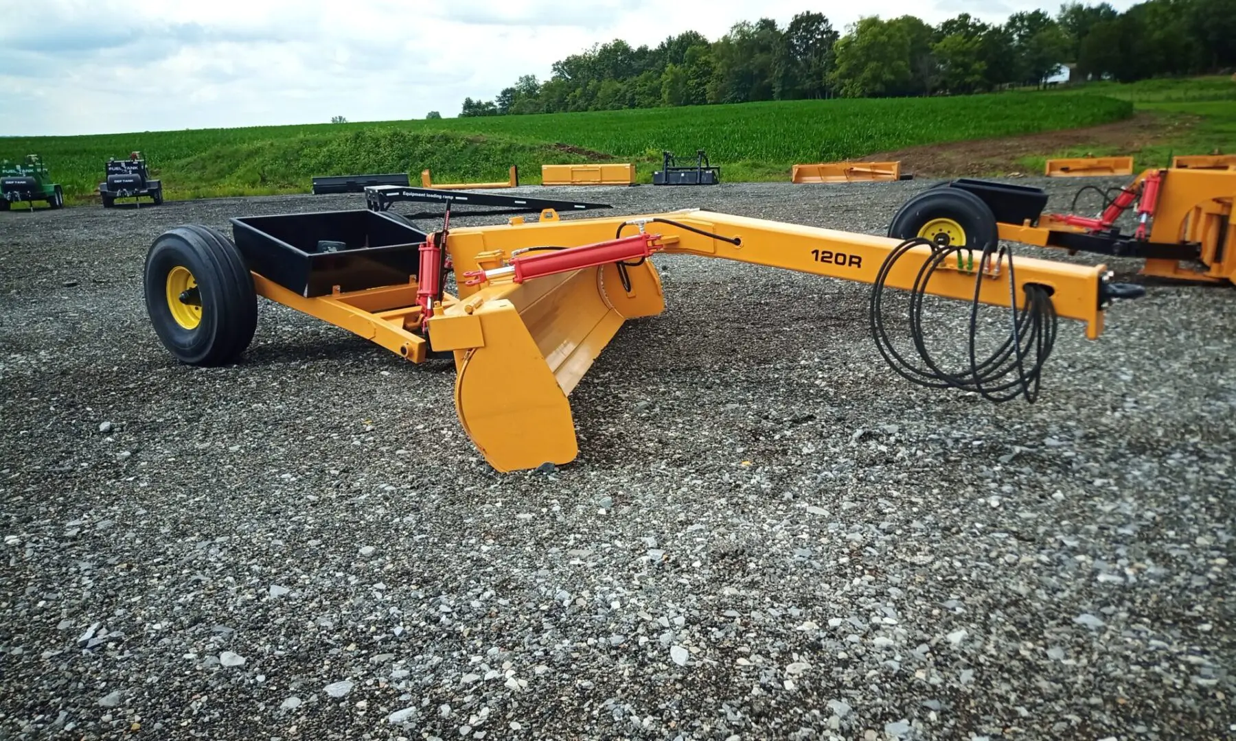 Yellow grader with black tires on gravel.