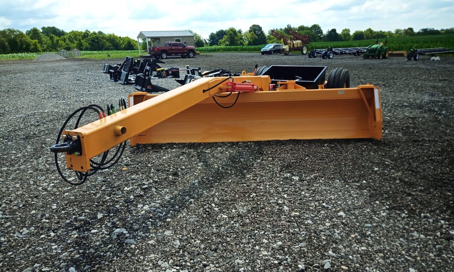 Yellow tractor blade with hydraulics.