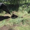 Backhoe digging in grassy field.