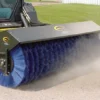 Here's an alt tag for the image: Loader sweeping with a large brush.