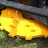 Yellow rotary cutter on green grass.