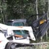 White skid steer cutting trees.