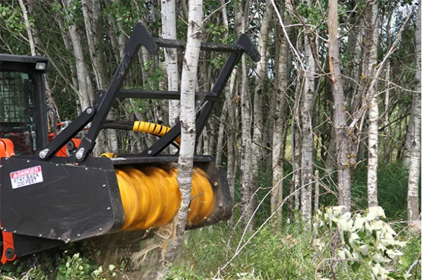 Tree cutter on a tractor clearing trees.