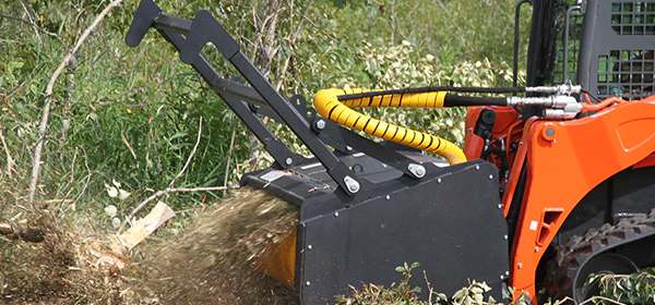 Here's an alt tag for the image: > Skid steer clearing brush and debris.