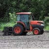Red tractor cultivating a field.