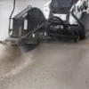 Here's an alt tag for the image: Skid steer cutting concrete pavement.