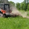Orange skid steer mowing field.