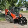 Orange skid steer cutting asphalt.
