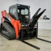 Orange track skid steer with forks.