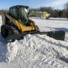 Yellow Cat skid steer clearing snow.