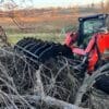 Red skid steer clearing brush.
