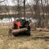 Skid steer lifting a tree log.