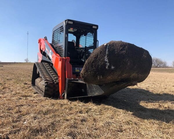 Tracked skid steer lifting large sod.