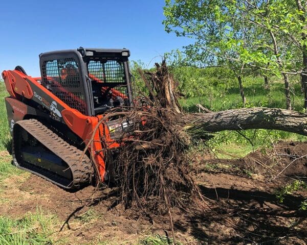 Orange skid steer removing tree stump.