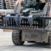 Here's an alt tag for the image: `Skid steer with grapple bucket attachment`